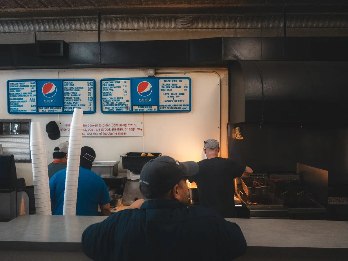 Bustling quick service restaurant kitchen prep line under warm lights